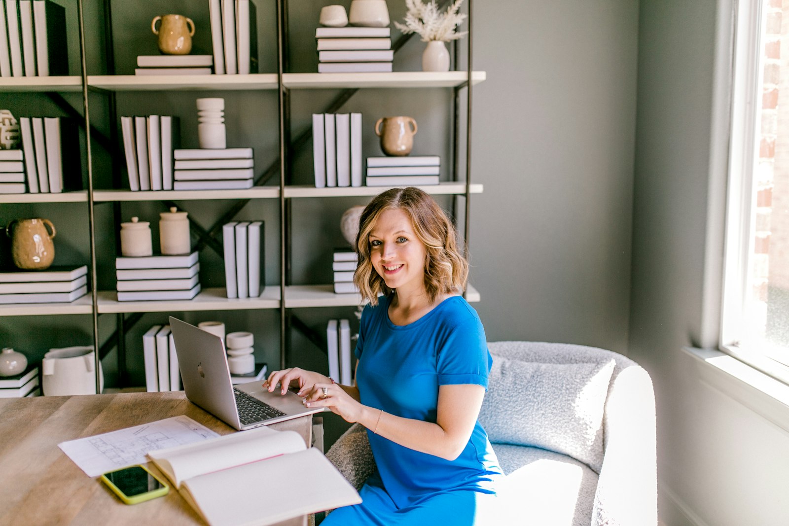 A small-business owner smiling at her laptop in a bright office